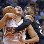 Phoenix Suns guard Devin Booker, left, gets fouled by Miami Heat guard Wayne Ellington as Booker goes up for a shot during the first half of an NBA basketball game Tuesday, Jan. 3, 2017, in Phoenix. (AP Photo/Ross D. Franklin)