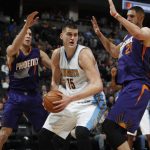Denver Nuggets forward Nikola Jokic, center, of Serbia, looks to pass the ball as Phoenix Suns guard Devin Booker, left, and center Alex Len, of the Ukraine, defend in the first half of an NBA basketball game Thursday, Jan. 26, 2017, in Denver. (AP Photo/David Zalubowski)