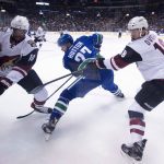 Vancouver Canucks defenseman Ben Hutton (27) fights for control of the puck with Arizona Coyotes left wing Anthony Duclair (10) and Arizona Coyotes center Christian Dvorak (18) during the first period of an NHL hockey game, Wednesday, Jan. 4, 2017 in Vancouver, British Columbia. (Jonathan Hayward/The Canadian Press via AP)