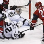 Los Angeles Kings goalie Peter Budaj, top center, makes a save on a shot by Arizona Coyotes left wing Brendan Perlini (29) as Kings center Trevor Lewis (22) defends during the third period of an NHL hockey game Tuesday, Jan. 31, 2017, in Glendale, Ariz. The Kings defeated the Coyotes 3-2. (AP Photo/Ross D. Franklin)