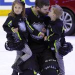 FILE - In this Jan. 25, 2015, file photo, Team Foligno's Brent Burns of the San Jose Sharks gets a kiss from his son after bringing his son and daughter onto the ice at the conclusion of the NHL All-Star hockey game in Columbus, Ohio. A five-day bye week for each team is a new wrinkle added to the NHL this season so players can get a breather during the second half of a grueling, 82-game grind. Mike Smith felt weird that other teams were playing while he and the Arizona Coyotes were off and relaxing, but that didn't deter the All-Star goaltender from going sledding with his kids and taking advantage of the downtime. (AP Photo/Gene J. Puskar, File)
