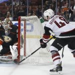 Anaheim Ducks goalie John Gibson, left, stops a puck off the stick of Arizona Coyotes's Jordan Martinook (48) as Arizona's Christian Dvorak (18) looks on in the first period of an NHL hockey game in Anaheim, Calif., Friday, Jan. 6, 2017. (AP Photo/Christine Cotter)