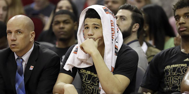 Phoenix Suns' Devin Booker watches from the bench during the second half of an NBA basketball game ...