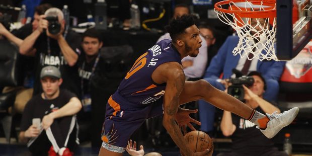 Phoenix Suns forward Derrick Jones Jr., leaps over three people during the slam-dunk contest as par...