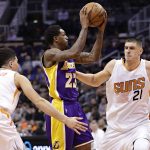 Los Angeles Lakers guard Lou Williams (23) passes between Phoenix Suns center Alex Len (21) and guard Devin Booker (1) during the first half of an NBA basketball game, Wednesday, Feb. 15, 2017, in Phoenix. (AP Photo/Matt York)
