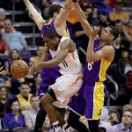 Phoenix Suns guard Brandon Knight (11) passes between Los Angeles Lakers guard Jordan Clarkson (6) and forward Larry Nance Jr. during the first half of an NBA basketball game, Wednesday, Feb. 15, 2017, in Phoenix. (AP Photo/Matt York)
