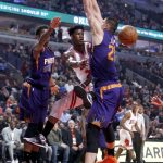 Chicago Bulls' Jimmy Butler, center, passes between Phoenix Suns' Marquese Chriss, left, and Alex Len during the first half of an NBA basketball game Friday, Feb. 24, 2017, in Chicago. (AP Photo/Charles Rex Arbogast)