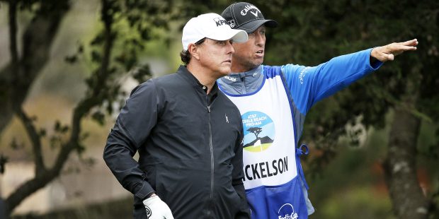 Phil Mickelson listens to his caddie Jim "Bones" Mackay before hitting from the fifth tee of the Mo...
