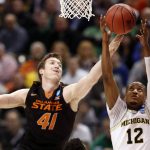 Oklahoma State's Mitchell Solomon (41) and Michigan's Muhammad-Ali Abdur-Rahkman reach for the ball during the second half of a first-round game in the men's NCAA college basketball tournament Friday, March 17, 2017, in Indianapolis, Mo. Michigan won 92-91. (AP Photo/Jeff Roberson)