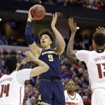 Michigan forward D.J. Wilson (5) shoots over Louisville forward Anas Mahmoud (14) and forward Ray Spalding (13) during the second half of a second-round game in the men's NCAA college basketball tournament in Indianapolis, Sunday, March 19, 2017. Michigan defeated Louisville 73-69. (AP Photo/Michael Conroy)
