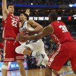 Villanova guard Josh Hart, center, drives to the basket against Wisconsin forward Ethan Happ, left,  and forward Vitto Brown, right, with three seconds remaining in the second half of a second-round men's college basketball game in the NCAA Tournament, Saturday, March 18, 2017, in Buffalo, N.Y.  (AP Photo/Bill Wippert)