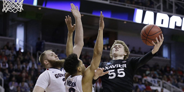 Xavier guard J.P. Macura (55) drives to the basket as Gonzaga guard Silas Melson (0) and center Prz...