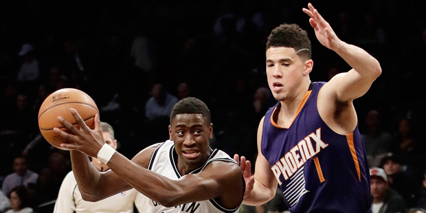 Brooklyn Nets' Caris LeVert (22) drives past Phoenix Suns' Devin Booker (1) during the first half o...