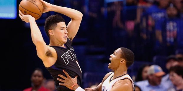 Phoenix Suns guard Devin Booker, left, looks to pass as Oklahoma City Thunder guard Russell Westbro...