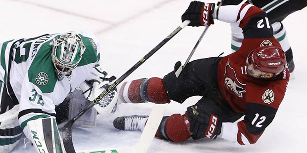 Arizona Coyotes' Brad Richardson (12) gets pulled down by Dallas Stars' Jamie Benn, top right, as h...