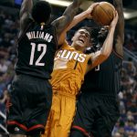 Phoenix Suns guard Devin Booker (1) drives to the basket between Houston Rockets' Lou Williams (12) and Montrezl Harrell during the second half of an NBA basketball game, Sunday, April 2, 2017, in Phoenix. (AP Photo/Ralph Freso)