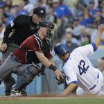 Los Angeles Dodgers' Corey Seager, right, scores on a sacrifice fly by Yasiel Puig as Arizona Diamondbacks catcher Jeff Mathis applies a late tag during the first inning of a baseball game, Saturday, April 15, 2017, in Los Angeles. (AP Photo/Jae C. Hong)