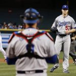 Los Angeles Dodgers' Alex Wood (57) waits for a new baseball as he looks to catcher Yasmani Grandal, center, after Wood gave up a home run to Arizona Diamondbacks' A.J. Pollock, left, during the first inning of a baseball game Friday, April 21, 2017, in Phoenix. (AP Photo/Ross D. Franklin)