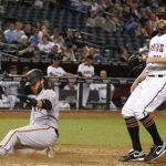 San Francisco Giants' Brandon Crawford, left, scores a run on a wild pitch from Arizona Diamondbacks' Tom Wilhelmsen, right, during the eighth inning of a baseball game Wednesday, April 5, 2017, in Phoenix. The Diamondbacks defeated the Giants 8-6. (AP Photo/Ross D. Franklin)