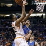 Phoenix Suns forward T.J. Warren, left, drives to the basket as Dallas Mavericks' Dwight Powell, center, defends during the second half of an NBA basketball game, Sunday, April 9, 2017, in Phoenix. The Suns defeated the Mavericks 124-111. (AP Photo/Ralph Freso)