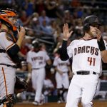 Arizona Diamondbacks' Jeremy Hazelbaker (41) applauds as he scores a run while San Francisco Giants' Buster Posey, left, watches the movement of the ball in the infield during the sixth inning of a baseball game Wednesday, April 5, 2017, in Phoenix. (AP Photo/Ross D. Franklin)
