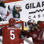 Arizona Coyotes' Mike Smith, right, takes a puck off the face mask as Minnesota Wild's Charlie Coyle (3) and Coyotes' Connor Murphy (5) look on during the first period of an NHL hockey game Saturday, April 8, 2017, in Glendale, Ariz. (AP Photo/Ross D. Franklin)