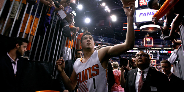 Phoenix Suns guard Devin Booker (1) hands an autographed shoe back to a fan as he walks off the cou...