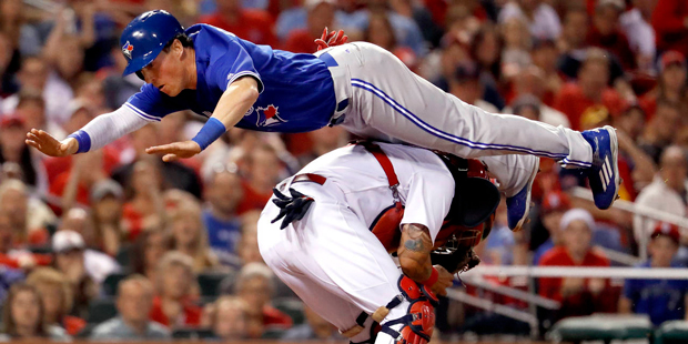 Toronto Blue Jays' Chris Coghlan leaps over St. Louis Cardinals catcher Yadier Molina to score duri...
