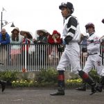 Some jockeys walk through the paddock in a race before the 143rd running of the Kentucky Derby horse race at Churchill Downs Saturday, May 6, 2017, in Louisville, Ky. (AP Photo/John Minchillo)