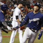 Milwaukee Brewers' Orlando Arcia (3) slaps hands with Eric Sogard, left, after Arcia scored a run, while Arizona Diamondbacks pitcher T.J. McFarland, middle, walks back to the mound during the sixth inning of a baseball game Friday, June 9, 2017, in Phoenix. (AP Photo/Ross D. Franklin)