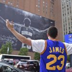 Cleveland Cavaliers fan Jordan Phillips poses for a photo in front of a poster featuring Cleveland Cavaliers forward LeBron James, before Game 4 of the basketball's NBA Finals between the Cavaliers and the Golden State Warriors, Friday, June 9, 2017, in Cleveland. (AP Photo/David Dermer)