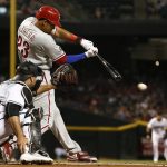 Philadelphia Phillies' Aaron Altherr (23) knocks in a run with an infield ground ball as Arizona Diamondbacks' Chris Iannetta, left, reaches out with his glove during the first inning of a baseball game Friday, June 23, 2017, in Phoenix. (AP Photo/Ross D. Franklin)