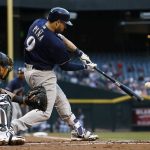 Milwaukee Brewers' Manny Pina connects for a two-run double as Arizona Diamondbacks' Jeff Mathis, left, watches during the first inning of a baseball game Friday, June 9, 2017, in Phoenix. (AP Photo/Ross D. Franklin)