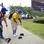 Golden State Warrior fans Tom Harley, right, and David De Le Garza use brooms to indicate a potential sweep, while looking at a poster featuring Cleveland Cavaliers forward LeBron James before Game 4 of the basketball's NBA Finals between the Cavaliers and the Warriors, Friday, June 9, 2017, in Cleveland. (AP Photo/David Dermer)