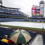 A few fans sit in the stands as the field is covered due to rain causing a delay to the first inning of a baseball game between the Arizona Diamondbacks and the Philadelphia Phillies, Saturday, June 17, 2017, in Philadelphia. (AP Photo/Chris Szagola)