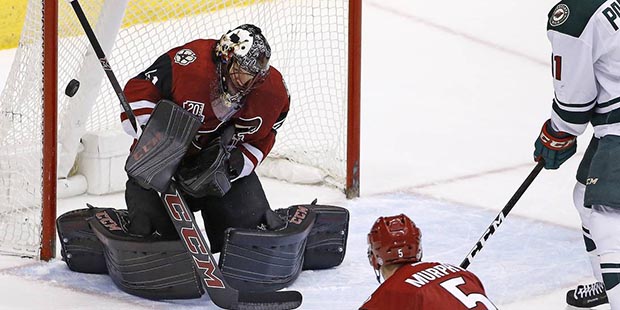 Arizona Coyotes' Mike Smith, left, makes a save on a shot from Minnesota Wild's Zach Parise (11) as...