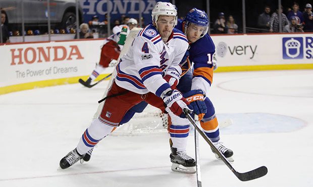 New York Rangers' Adam Clendening (4) and New York Islanders' Ryan Strome (18) reach for the puck d...