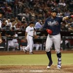Atlanta Braves' Johan Camargo, right, points to his teammates as he arrives at home plate after hitting a home run as Arizona Diamondbacks' Chris Iannetta, left, looks down at home plate during the eighth inning of a baseball game Tuesday, July 25, 2017, in Phoenix. (AP Photo/Ross D. Franklin)