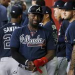Atlanta Braves' Brandon Phillips, middle, smiles as he walks through the dugout after scoring a run against the Arizona Diamondbacks during the first inning of a baseball game Wednesday, July 26, 2017, in Phoenix. (AP Photo/Ross D. Franklin)