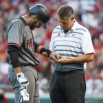 Arizona Diamondbacks' J.D. Martinez, left, winces in pain as a trainer checks his wrist after Martinez was struck while swinging at a pitch from Cincinnati Reds starting pitcher Tim Adleman in the fourth inning of a baseball game, Wednesday, July 19, 2017, in Cincinnati. (AP Photo/John Minchillo)