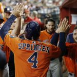 Houston Astros' George Springer (4) celebrates his run scored against the Arizona Diamondbacks with hitting coach Dave Hudgens, left, Max Stassi, second from right, and Brad Peacock, right, during the second inning of a baseball game Tuesday, Aug. 15, 2017, in Phoenix. (AP Photo/Ross D. Franklin)