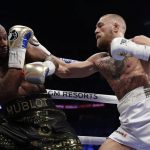 Conor McGregor, right, hits Floyd Mayweather Jr. in a super welterweight boxing match Saturday, Aug. 26, 2017, in Las Vegas. (AP Photo/Isaac Brekken)