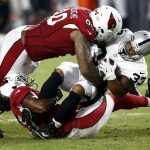 Oakland Raiders running back DeAndre Washington (33) is hit by Arizona Cardinals defensive tackle Robert Nkemdiche (90) and linebacker Josh Bynes (45) during the first half of an NFL preseason football game, Saturday, Aug. 12, 2017, in Glendale, Ariz. (AP Photo/Ross D. Franklin)