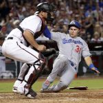 Los Angeles Dodgers' Joc Pederson (31) scores on a base hit by Yasiel Puig as Arizona Diamondbacks catcher Jeff Mathis waits for the throw during the seventh inning of a baseball game, Wednesday, Aug. 9, 2017, in Phoenix. (AP Photo/Matt York)