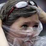 A baseball fan puts on a plastic poncho on as she watches a baseball game between the Arizona Diamondbacks and the Chicago Cubs in the first inning, Thursday, Aug. 3, 2017, in Chicago. (AP Photo/Nam Y. Huh)