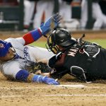Chicago Cubs' Javier Baez, left, reaches for the plate as he is tagged out by Arizona Diamondbacks catcher Jeff Mathis while trying to score from third base on an infield ground ball by teammate Albert Almora Jr. during the fifth inning of a baseball game, Saturday, Aug. 12, 2017, in Phoenix. The call was upheld by replay after the Cubs challenged the play. (AP Photo/Ralph Freso)
