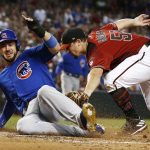 Chicago Cubs' Kris Bryant, left, scores a run ahead of a tag by Arizona Diamondbacks pitcher Zack Godley, right, during the first inning of a baseball game, Sunday, Aug 13, 2017, in Phoenix. The Cubs' Bryant scored on a wild pitch by the Diamondbacks' Godley. (AP Photo/Ross D. Franklin)