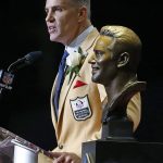 Former NFL quarterback Kurt Warner speaks next to a bust of him during inductions at the Pro Football Hall of Fame on Saturday, Aug. 5, 2017, in Canton, Ohio. (AP Photo/Ron Schwane)