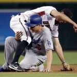 Arizona Diamondbacks' Adam Rosales is held up by Los Angeles Dodgers Corey Seager (5) after throwing to first on a double play hit into by Justin Turner during the first inning of a baseball game, Wednesday, Aug. 9, 2017, in Phoenix. (AP Photo/Matt York)