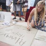 Bethany Hamilton carves her name into the concrete in front of Huntington Surf and Sport as part of her induction into the Surfers' Hall of Fame in Huntington Beach, Calif., Friday, Aug. 4, 2017.  Hamilton lost her arm in a shark attack in 2003. (Nick Agro/The Orange County Register via AP)